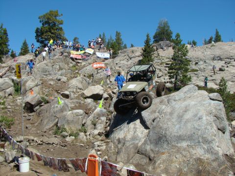 1989 Ford Bronco - A modified off-road buggy navigates a steep, rocky course with spectators watching from above.