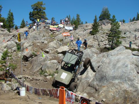 1989 Ford Bronco - Custom off-road buggy tackles a challenging rock crawling course with spectators watching from the hillside.