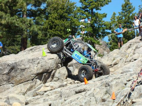1989 Ford Bronco - A custom-built off-road buggy navigates a steep, rocky course with spectators watching from above.