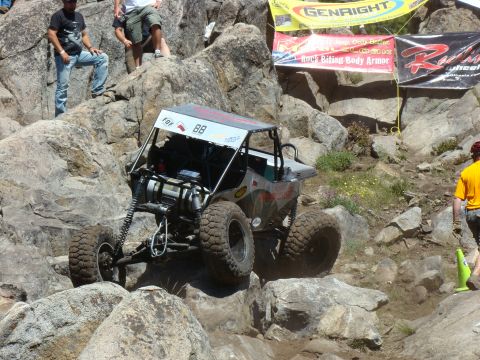 1989 Ford Bronco - A custom off-road buggy navigates a challenging rocky course with spectators watching from above.