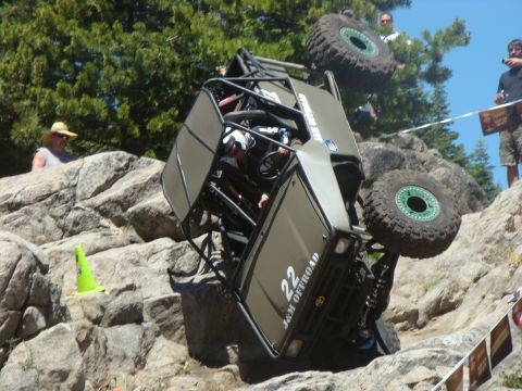 1989 Ford Bronco - An off-road vehicle is overturned on a rocky incline during a competition, with spectators watching.