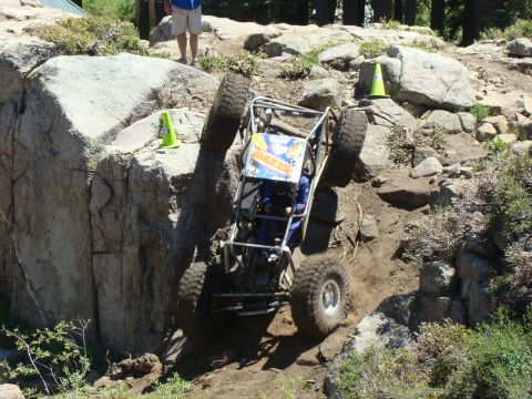 1989 Ford Bronco - This custom off-road vehicle navigates a challenging rocky terrain, with one wheel lifted high off the ground.