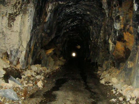 1989 Ford Bronco - A view down a dark, narrow mine tunnel, showing rough rock walls and fallen debris.
