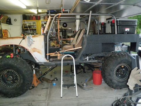 1961 International Scout 800 - Side view of a custom off-road vehicle undergoing modifications in a garage setting.