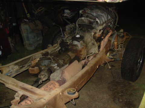 1983 Ford Bronco - The chassis and engine of a vehicle are shown disassembled, with various mechanical parts visible.