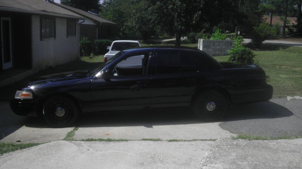 Black sedan parked in driveway, white SUV in background