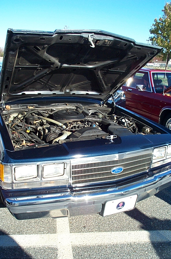 1991 Ford Crown Victoria LTD with hood open showing engine bay. Another maroon car is parked to the right