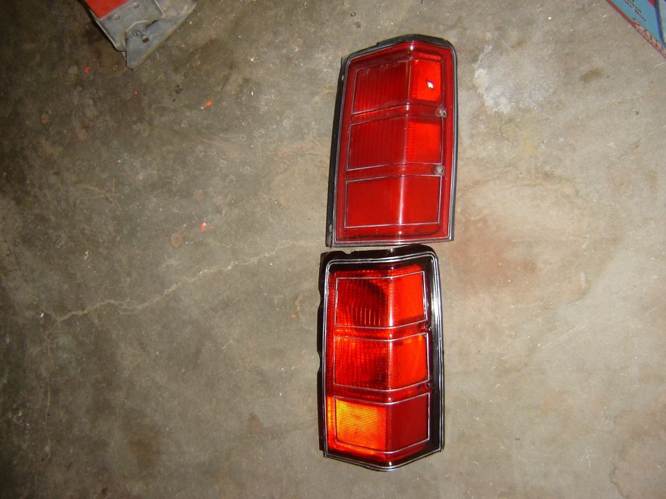 Two red car tail lights with chrome trim, one above the other