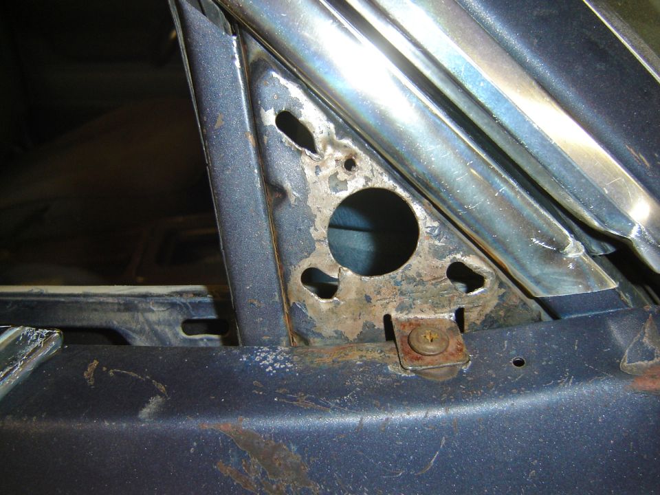 Close-up of a car's interior door frame, showing rust and metalwork