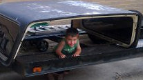 1979 Ford Bronco - A child is inside a truck cap that is loaded onto a trailer.