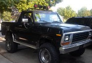 1979 Ford Bronco - A black 1978 Ford Bronco is parked outside on a sunny day, showing its off-road modifications.