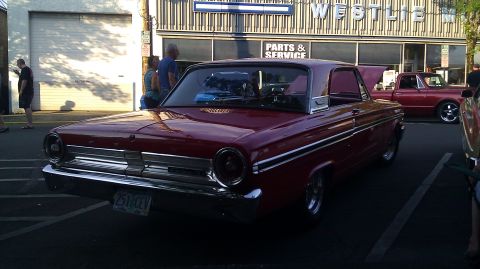 1964 Ford Fairlane - A red 1964 Ford Fairlane coupe is parked outside a business, with another vehicle visible.