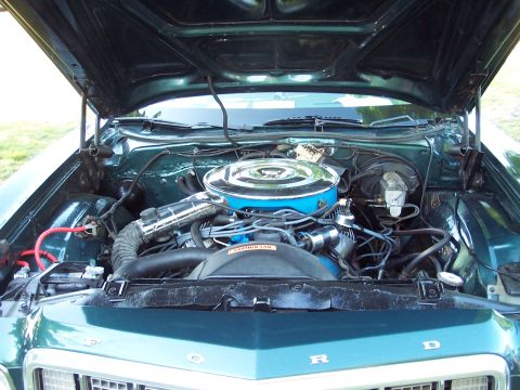1975 Ford Ranchero - The engine bay of a green Ford vehicle is shown with the hood raised.
