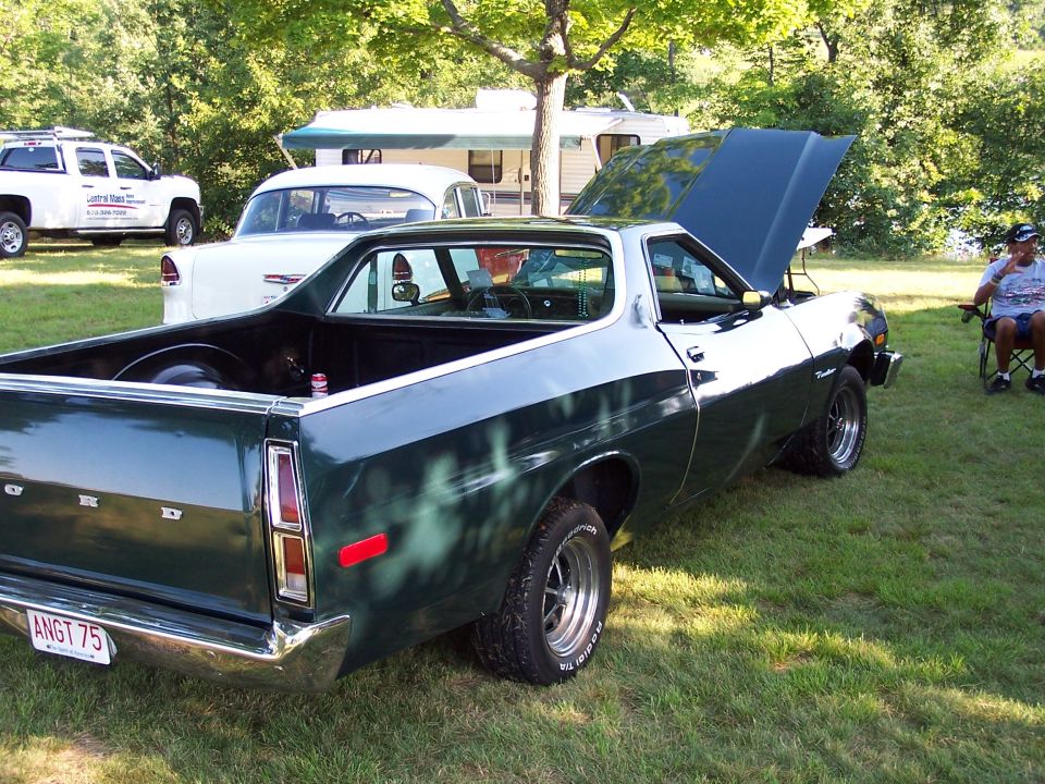 Dark green Ford Ranchero pickup rear 3/4 on grass, hood up, ANGT 75 plate