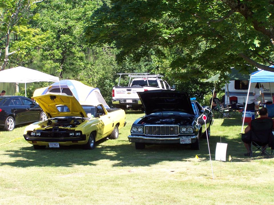 Yellow and dark green 1970s Ford Rancheros parked hoods-up at a grass car show