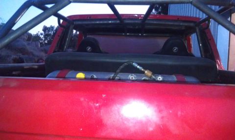 1978 Ford Bronco - Rear view of a red truck bed modified with a roll cage and visible seating.