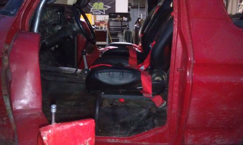 1978 Ford Bronco - Interior view of a red vehicle, racing seats with red harnesses and a roll cage.