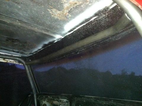 1978 Ford Bronco - The interior of a vehicle shows a roll cage and a worn headliner with visible rust.
