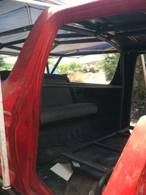 1978 Ford Bronco - The interior of a red SUV is visible, a custom roll cage and rear seating.