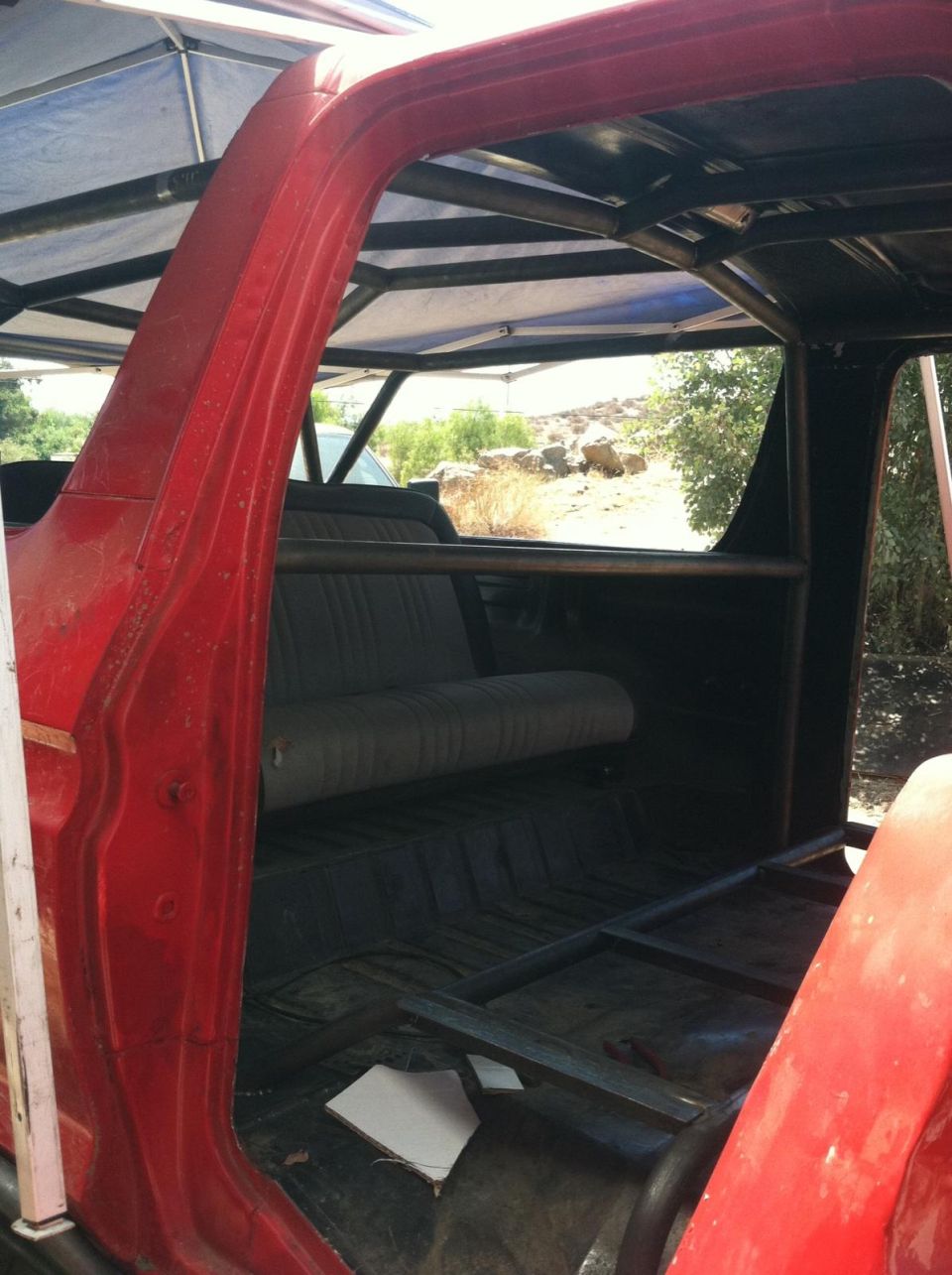 Interior of a red SUV with a roll cage installed. Shows the rear bench seat and floor