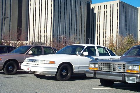 1991 Ford LTD Crown Victoria - A white 1992 Ford Crown Victoria sedan is parked in front of a large office building.