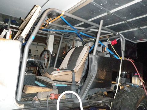1961 International Scout 800 - The interior of a vehicle is shown with a custom roll cage and a single bucket seat.