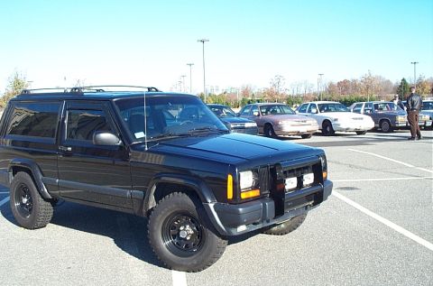 1991 Ford LTD Crown Victoria - A black Jeep Cherokee XJ is parked in a lot with several other sedans in the background.
