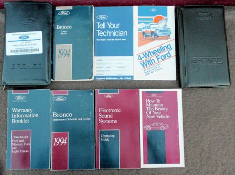 1994 Ford Bronco - Original 1994 Ford Bronco owner's literature laid out on a carpeted surface, including the 1994 Bronco Owner Guide, embossed Bronco vinyl d…