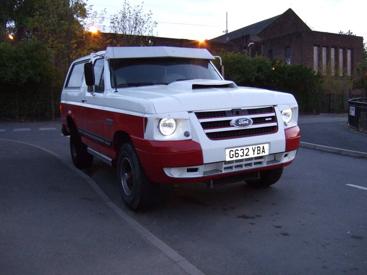 Two-tone red and white Ford Bronco with aftermarket grille and headlights. License plate G632 YBA