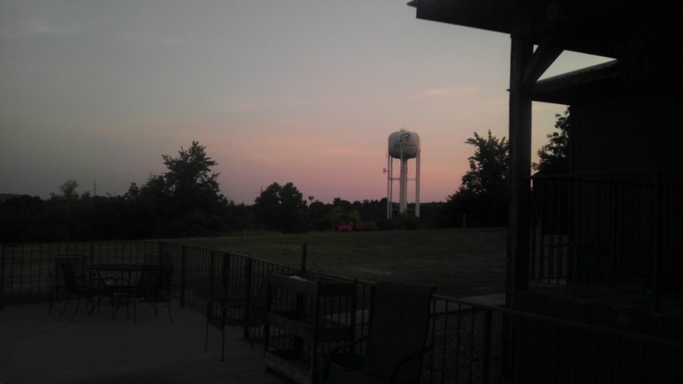 Water tower in a field at dusk, with a porch in the foreground