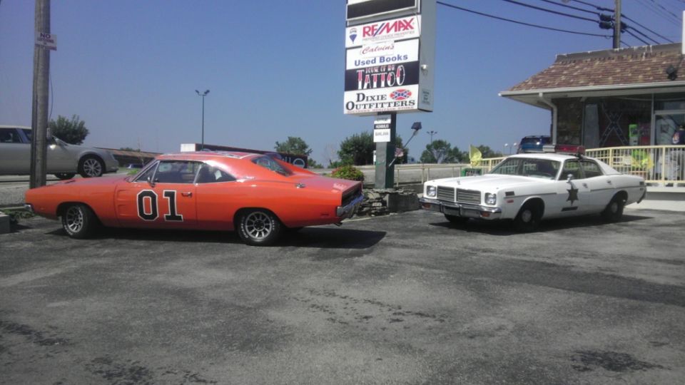 Orange 1970 Dodge Charger with "01" on door, parked next to a white police car
