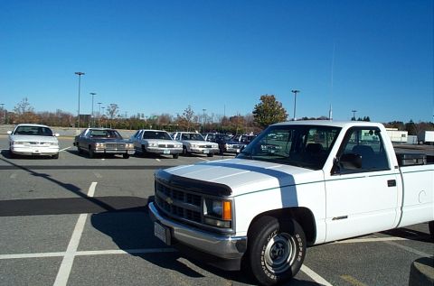 1991 Ford LTD Crown Victoria - A parking lot scene with a white pickup truck and multiple sedans on a sunny day.