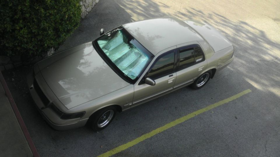 Tan 2000 Mercury Grand Marquis parked on asphalt with a yellow line