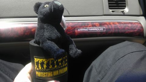 2000 Mercury Grand Marquis - A plush toy sits in a cup holder inside a 2000 Mercury Grand Marquis, with the model name visible on the dashboard trim.
