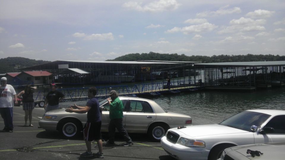 Silver sedan parked by a lake with a marina in the background