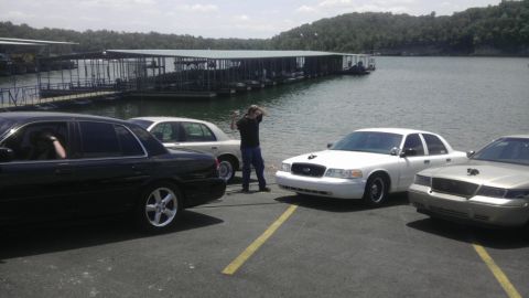 2000 Mercury Grand Marquis - Multiple sedans are parked near a body of water with docks and trees in the background.