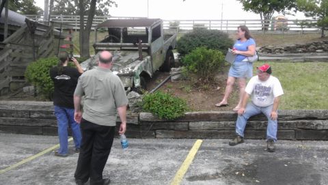 2000 Mercury Grand Marquis - A group of people observe a derelict truck in an outdoor setting.