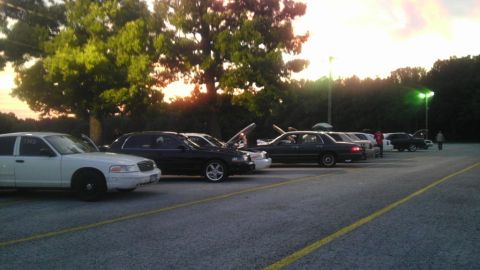 2000 Mercury Grand Marquis - Several sedans, including a white 2000 Mercury Grand Marquis, are parked in a lot during the day.