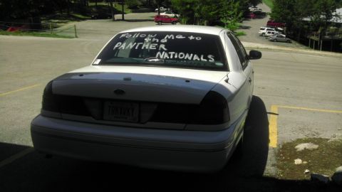 2000 Mercury Grand Marquis - A white sedan is parked outside, with text written on its rear window advertising an event.