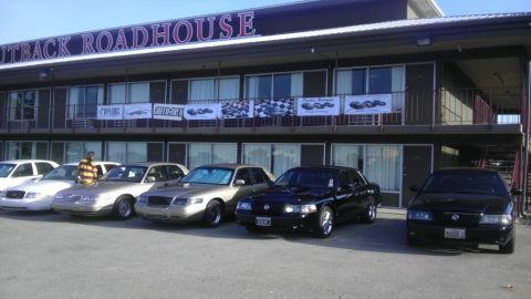 2000 Mercury Grand Marquis - A lineup of Mercury Grand Marquis sedans are parked in front of the Outback Roadhouse building.