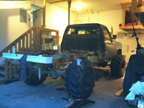 1983 Chevrolet C/K Pickup - This pickup truck appears to be undergoing significant modifications, including the installation of oversized tires and a lifted chassis.