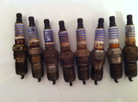 2001 Mercury Grand Marquis - A collection of eight used spark plugs, some showing signs of wear and tear.