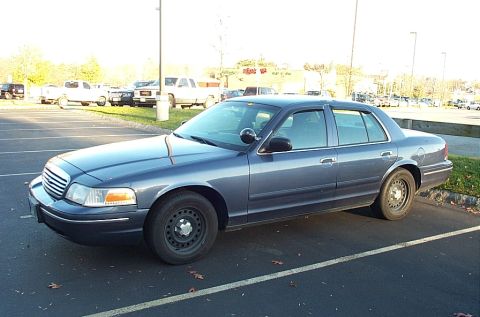 1991 Ford LTD Crown Victoria - A blue Ford Crown Victoria sedan, likely a police interceptor, is parked in an outdoor lot.