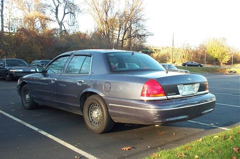 1991 Ford LTD Crown Victoria - A dark blue Ford Crown Victoria is parked in a lot, showing its rear end and license plate.