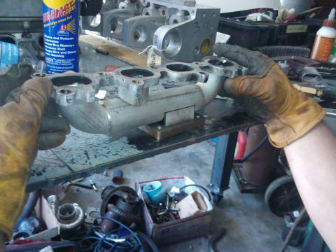 1995 Ford Probe - Close-up of an engine intake manifold being held by gloved hands in a workshop setting.