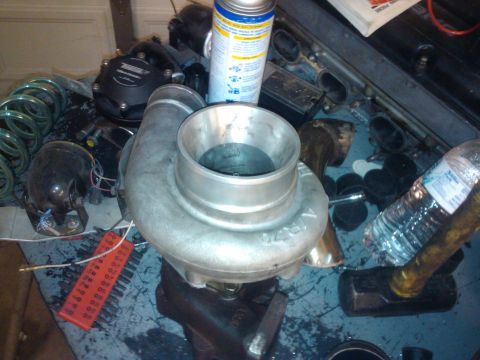 1995 Ford Probe - Various automotive engine components, including a turbocharger and intake manifold, are spread across a cluttered workbench.