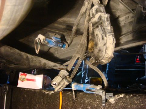 2001 Mercury Grand Marquis - Close-up view of the underside of a vehicle, showing brake lines and electrical connectors, with a box visible in the lower left.