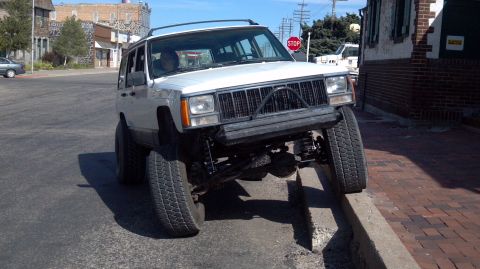1995 Jeep Cherokee - White 1995 Jeep Cherokee with aftermarket bumper and lifted suspension is shown on a curb.