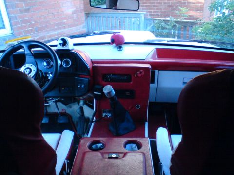 1989 Ford Bronco - The interior of a 1987 Ford Bronco shows a red dashboard with a custom gauge and aftermarket shifter.