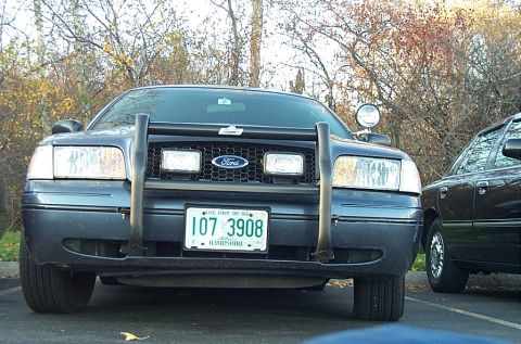 1991 Ford LTD Crown Victoria - A dark blue Ford Crown Victoria Police Interceptor is seen from the front, parked next to another vehicle.